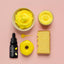Yellow cake batter with a bottle, spoon, and cake on a pink background
