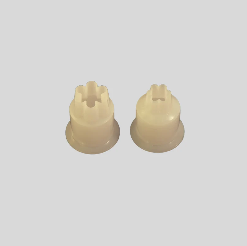 Two small off-white plastic cylindrical components with star-shaped top slots, shown on a plain light gray background.