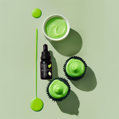 Green icing food colour including a bowl of icing, bottles, and cupcakes on a light green background