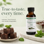 A bottle of Lorann Natural Peppermint Oil stands on a marble board beside chocolate pieces and mint leaves, with marketing text on a pale green background.
