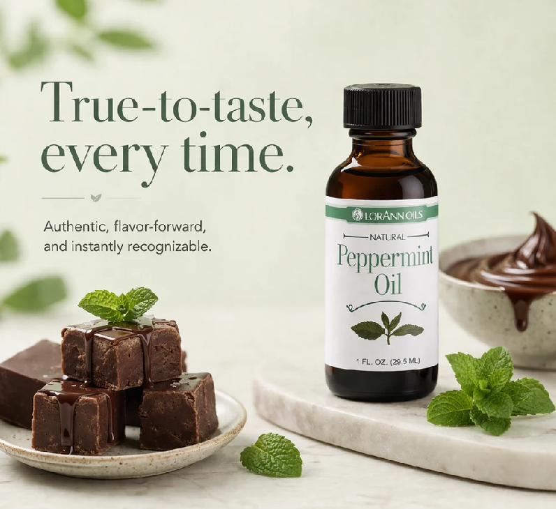 A bottle of Lorann Natural Peppermint Oil stands on a marble board beside chocolate pieces and mint leaves, with marketing text on a pale green background.