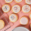 Decorative cookies with white icing and colorful sprinkles on a pink surface.