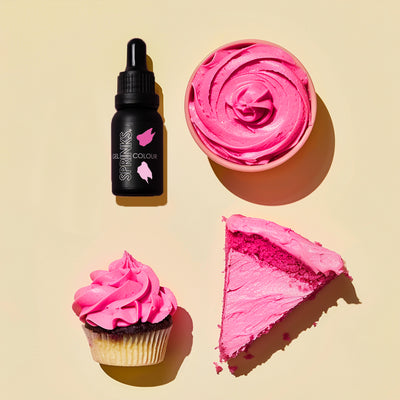 Black bottle with pink Sprinks logo, pink frosting on a cupcake and cake slice, pink whipped cream in a bowl on a beige background