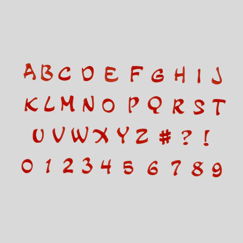 A red fondant alphabet and number cut out - displayed on a light gray background, including uppercase letters, symbols, and digits.