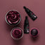 Cupcakes with burgundy frosting and two bottles of 'Sprinks' on a maroon background