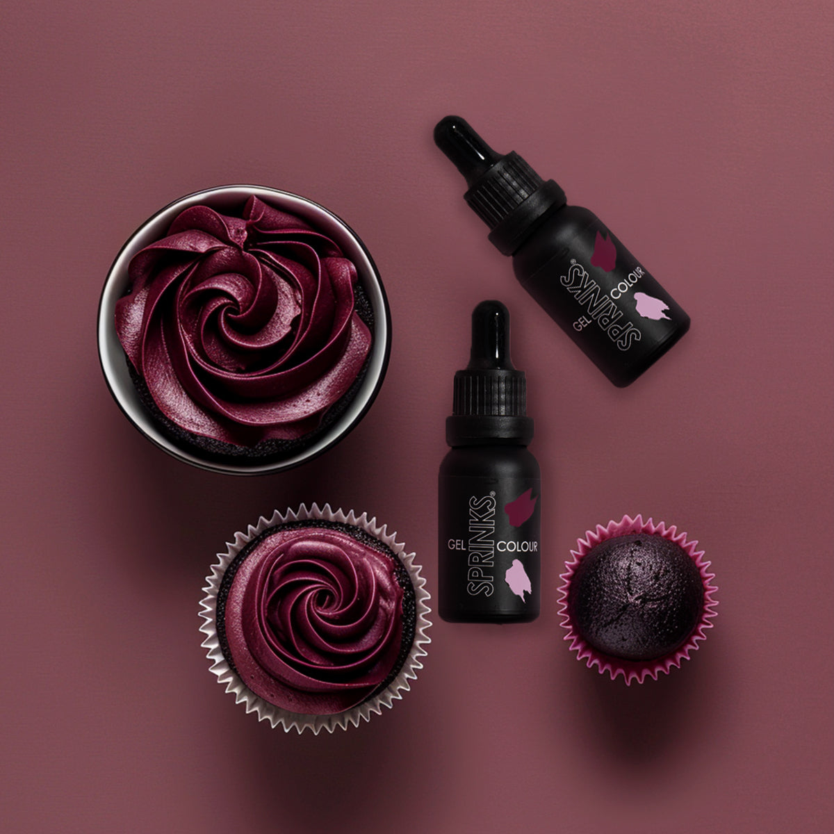 Cupcakes with burgundy frosting and two bottles of 'Sprinks' on a maroon background