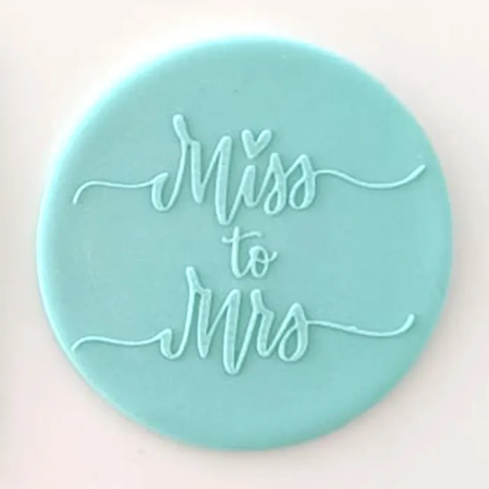 A round turquoise blue fondant plaque with the words 'Miss to Mrs' in raised script, shown against a plain light background.