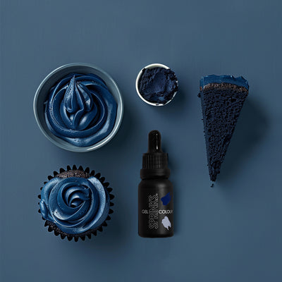 Blue-colored cake, cupcake, and bottle of Sprinks gel color on a blue background