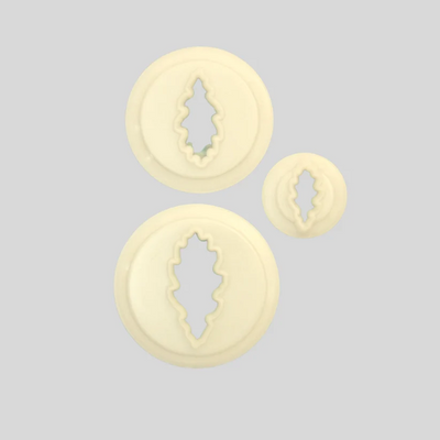 Three round cream-colored plastic  cutters in different sizes, shape dlike oak leaves, arranged on a solid light gray background.