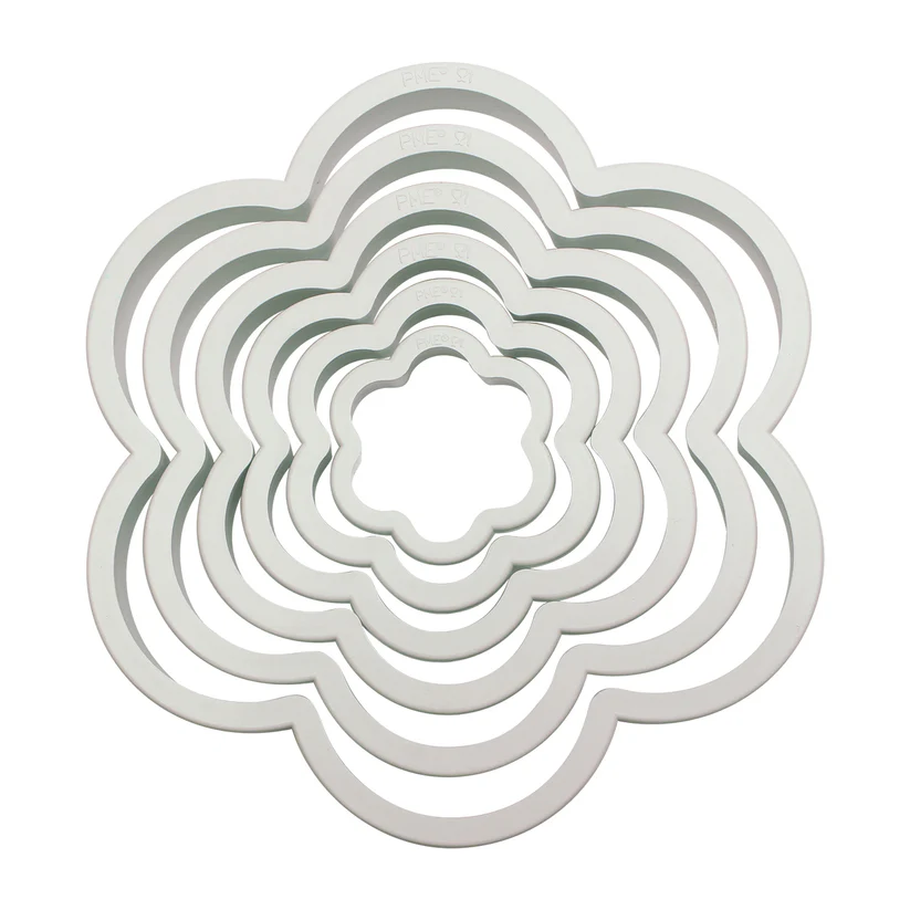 A set of nested flower-shaped plastic cookie cutters in a white colour, arranged concentrically on a solid white background.