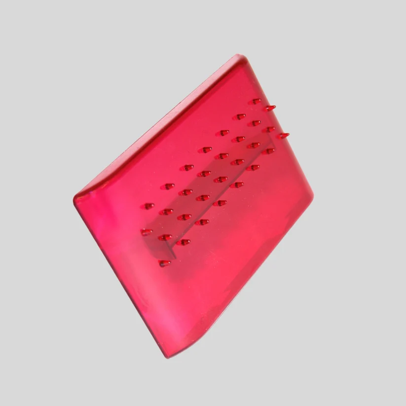 A translucent red rectangular tool with raised nubs, shown at an angle on a solid gray background. made by FMM for imprinting in to fondant