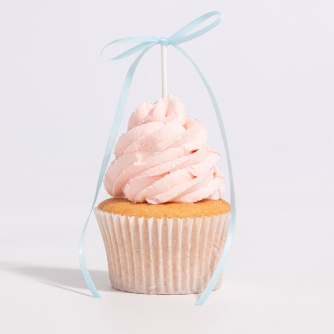 Cupcake with pink frosting and a blue ribbon on a light gray background