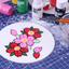 Floral painting on round white icing with Colour Mill paint bottles in the background.
