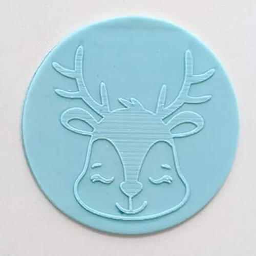 A light blue circular fondant plaque featuring a sleeping deer head with antlers, shown on a plain off-white background.