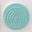 Teal circular fondant plaque with a rainbow and heart design on a light pink background