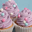 Cupcakes with purple frosting and colorful diamond sprinkles on a light blue background