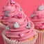 Cupcakes with pink frosting and decorative elements on a pink background