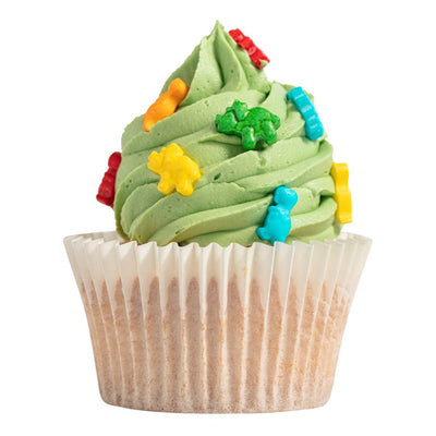 Cupcake with green frosting and colorful candy dinosaur decorations on a white background