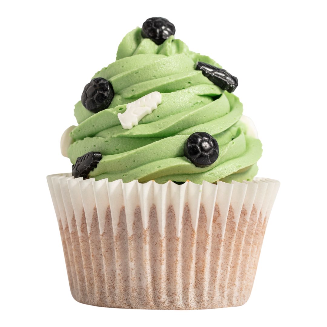 Cupcake with green frosting and soccer themed decorations on a white background