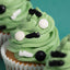 Green frosted cupcake with black and white soccer edible decorations on a teal background
