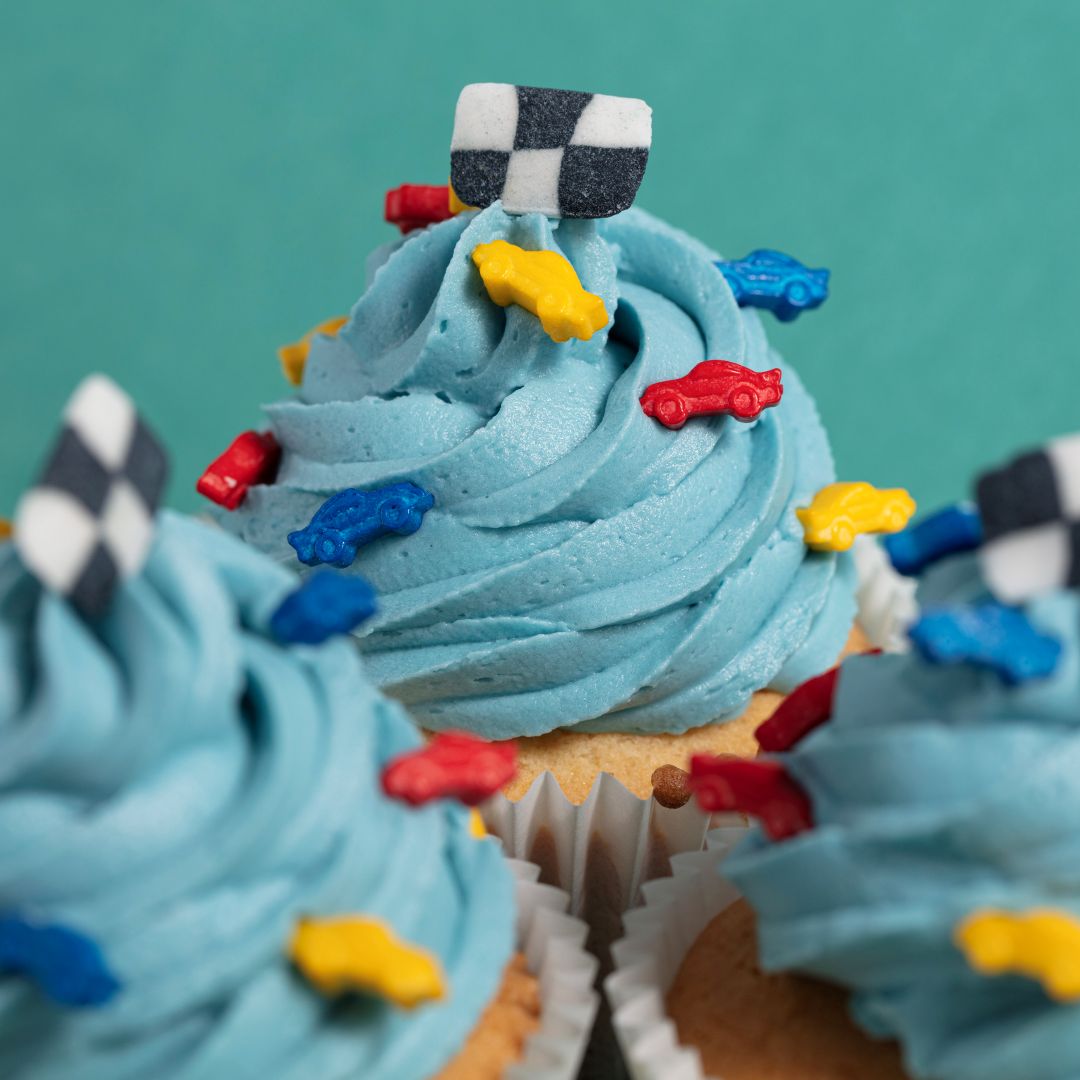 Cupcakes with blue frosting and edible racing themed sprinkles on a teal background