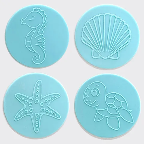 Four round light blue fondant plaques featuring embossed sea-themed designs: a seahorse, a scallop shell, a starfish, and a turtle, arranged in a 2x2 grid on a white background.