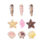 Nine seashell-shaped chocolates arranged in a 3x3 grid on a plain white background. The set includes various realistic shell designs in pink, brown, yellow, and cream colors.