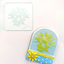 A clear embosser with the text 'Shine Bright' on a white background. With a finished cookie with a yellow and blue background.