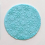 A round turquoise blue fondant icing decorative plaque featuring a repeating pattern of embossed spiders and spiderwebs on a light background.