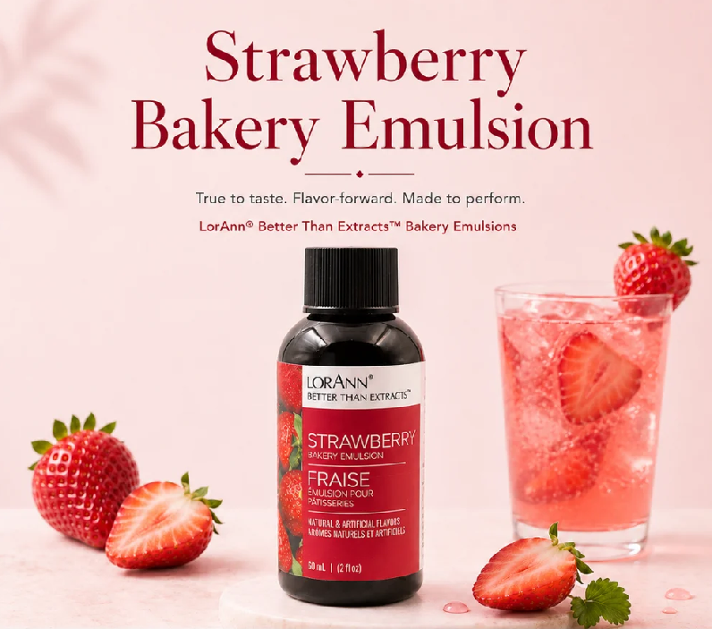 A bottle of LorAnn Strawberry Bakery Emulsion centered on a soft pink background, with large red headline text above. Fresh strawberries and a pink strawberry drink are arranged around the bottle as styled props.