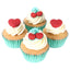 Four cupcakes with white frosting, red hearts, and cherries.