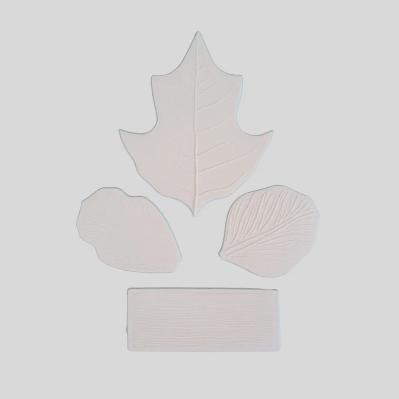 Four pale pinkish-beige textured leaf-shaped pieces arranged on a light gray background: one large leaf at the top, two smaller leaf shapes at the sides, and one rectangular piece at the bottom.