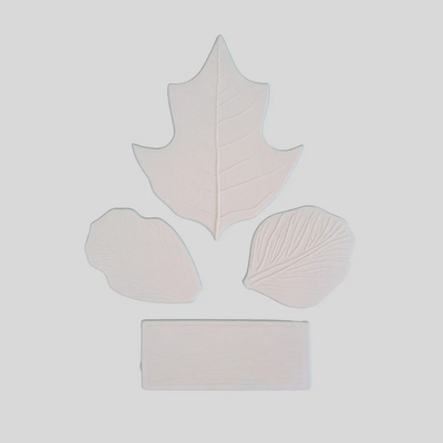 Four pale pinkish-beige textured leaf-shaped pieces arranged on a light gray background: one large leaf at the top, two smaller leaf shapes at the sides, and one rectangular piece at the bottom.