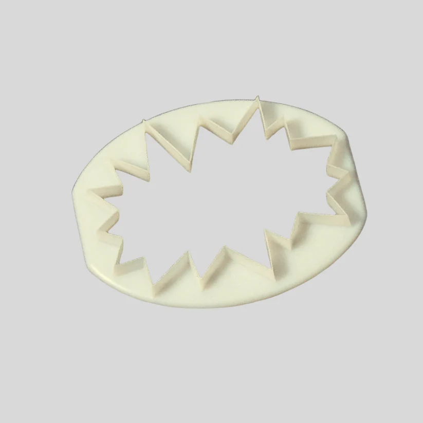 An off-white plasticcutter with a jagged, starburst-like inner edge, shown on a solid light gray background.