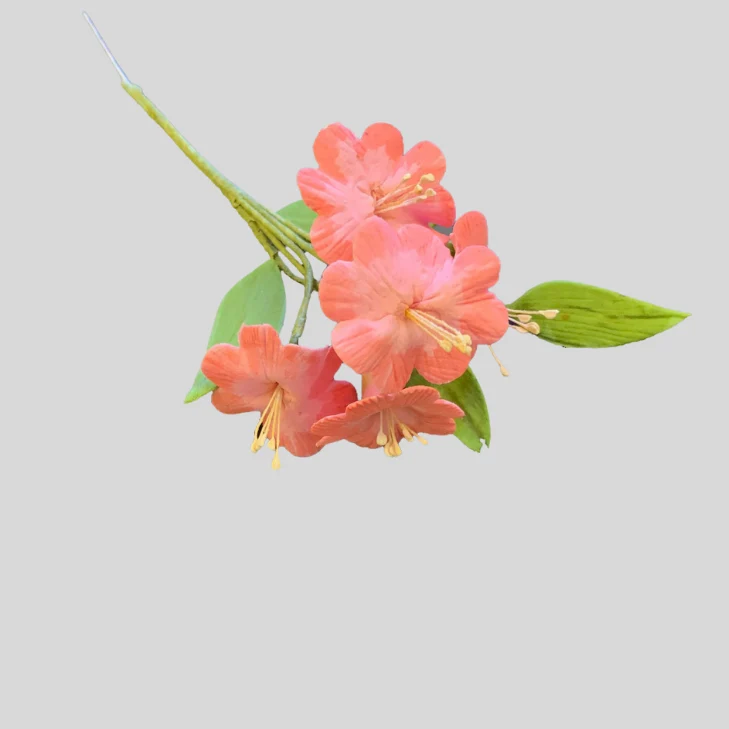 A single stem of gumpaste icing coral-pink flowers with green leaves on a plain light gray background.
