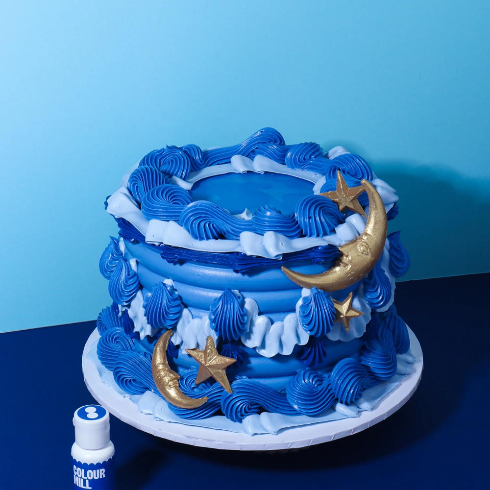 Blue and white cake with gold moon and star decorations on a blue background