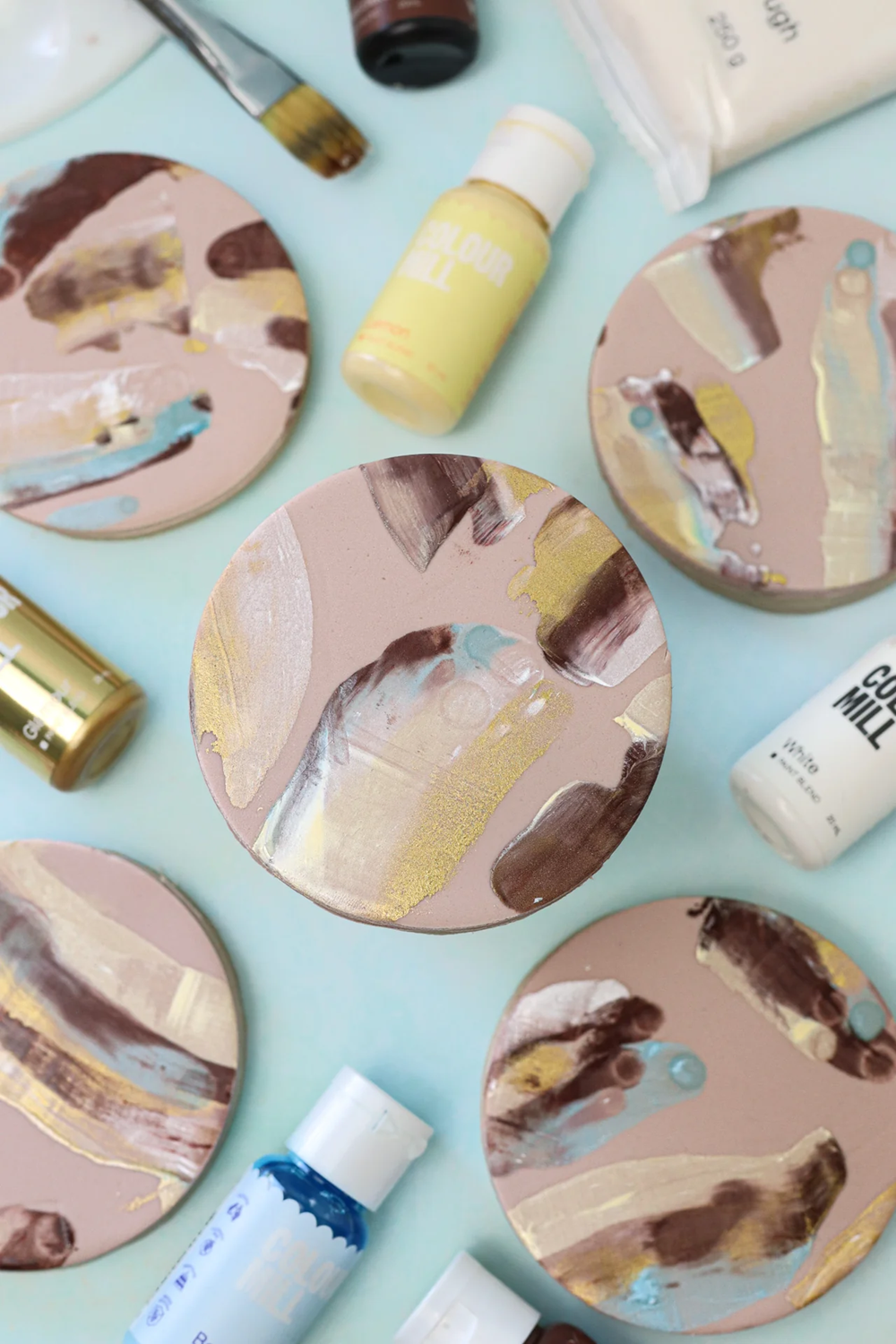 Example of round pinky beige cookies decorated with marbled brown, white, blue and gold Colourmill Edible Paint Blends