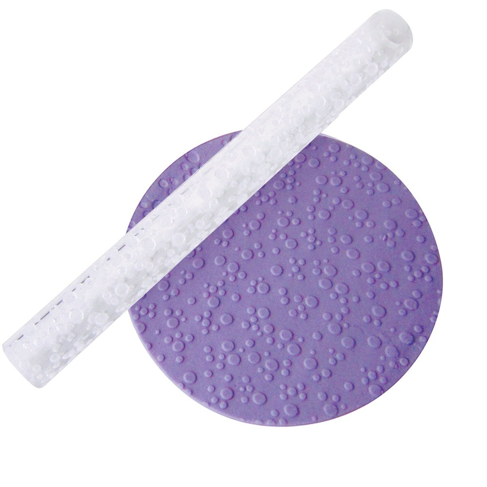 Acrylic rolling pin with an embossed design of bubbles or dots, alongside a purple fondant example made using it