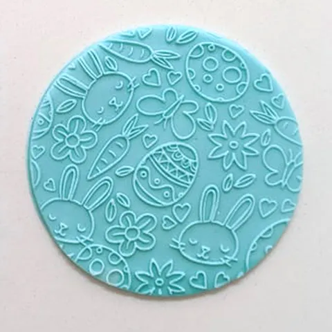 Round blue fondant circle with Easter-themed designs on a light pink background