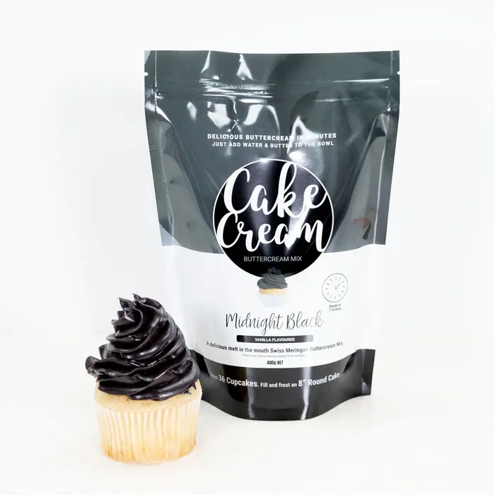 Bag of Cake Cream Midnight Black Buttercream Mix with a cupcake frosted with the product on a white background