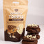 A 100g bag of GoBake Choccy Toppys (choc pearls) stands next to three chocolate cookies topped with white chocolate pearls, set against a clean white background.