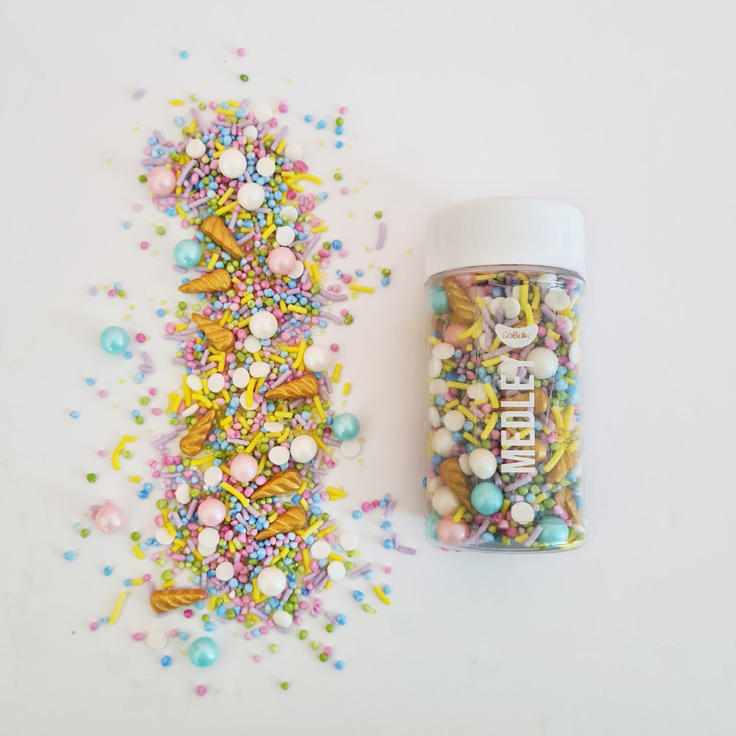 Colorful sprinkles and a container on a white background with unicorn horns and pretty colour sprinkles