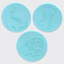 Three circular light blue fondant circles featuring embossed dinosaur designs, arranged on a plain light gray background.