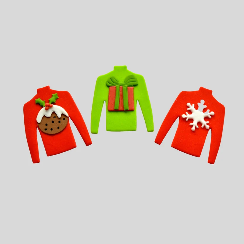 Three Christmas-themed fondant turtlenecks "ugly sweaters" displayed on a light gray background: a red sweater with a pudding decoration, a lime green sweater with a gift box on the back, and a red sweater with a white snowflake on the front.