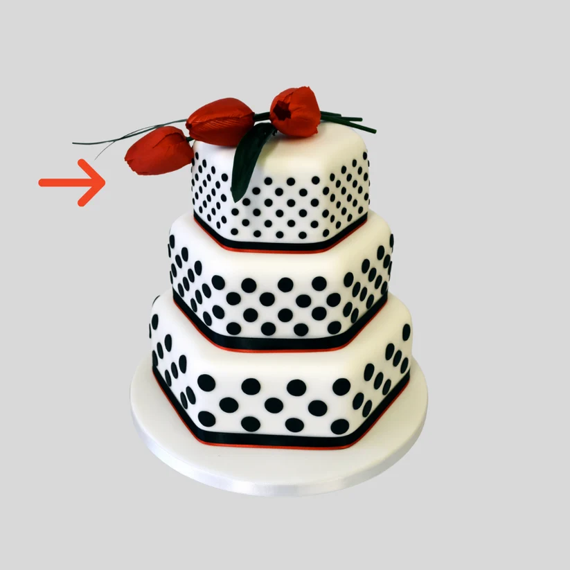 a cake with black polka dots on white fondant. Made with three tiers