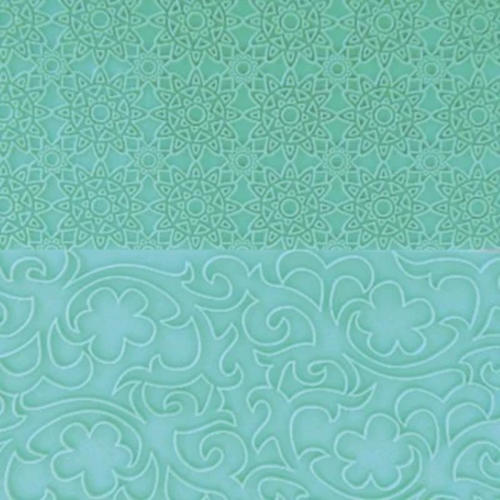 A close-up of a mint green textured surface with two distinct embossed patterns: a fine geometric mandala design on the top half, and a larger floral scrollwork design on the bottom half.
