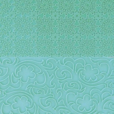 A close-up of a mint green textured surface with two distinct embossed patterns: a fine geometric mandala design on the top half, and a larger floral scrollwork design on the bottom half.
