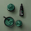 Green cupcakes with a container of green frosting and a bottle labeled 'Sprinkles Colour' on a green background.