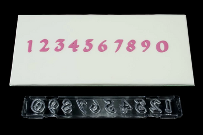 A set of clear plastic number cutters laid out next to their corresponding fondant icing number on a white background.
