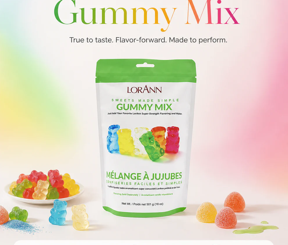 A bag of LorAnn Gummy Mix candy stands on a white surface against a soft pastel gradient background. The package is white with a green top and green text, and colorful gummy bears are printed on the front.